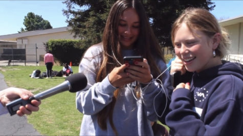 Two AGHS students share earbuds and laugh while they tell the mic what theyre listening to. 