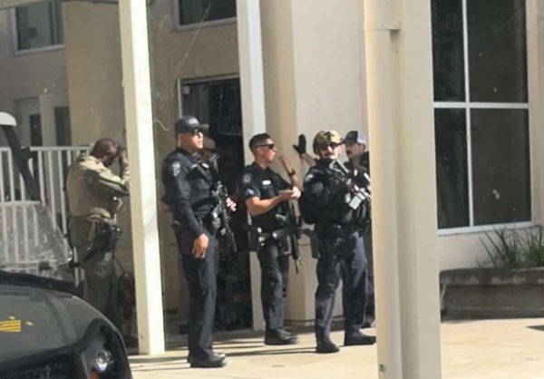 SWAT team lined up outside of office and main gate, visible to all students locked in the MPR.