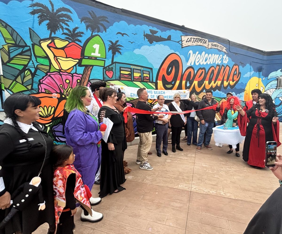 Scott Lakey cutting a ribbon to show the new mural at La Tapitia alongside VACO members happy at the new mural in the plaza

