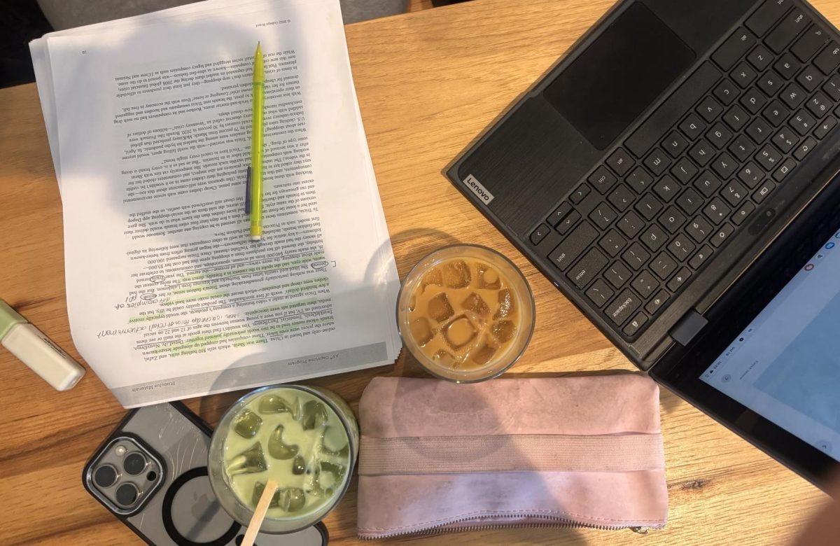 Notes, laptops, and a variety of study drinks fill the table as students study for upcoming exams. 