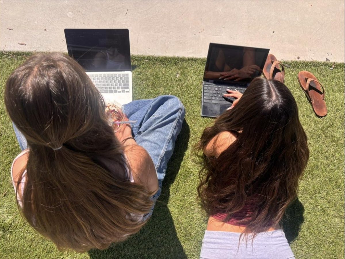 Depicts students on a sunny Saturday afternoon, tanning while catching up on school work. 